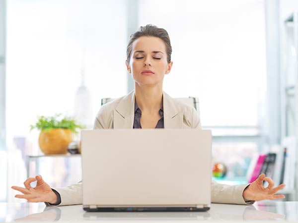 Frau meditiert am Arbeitsplatz
